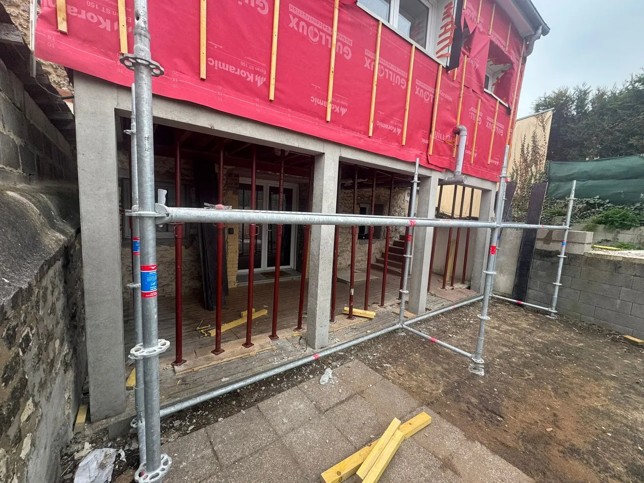 Extension de maison en construction avec étaiement métallique et écran sous-toiture rouge, chantier MVT Réno